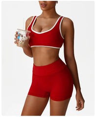 Person wearing a red sports bra and shorts set, holding a clear plastic cup.
