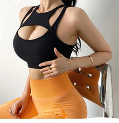 Person wearing a black sports bra and orange leggings sitting on a chair.