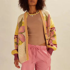 Person wearing a colorful patterned cardigan over a beige top and pink pants