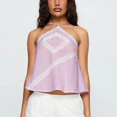 Woman wearing a pink halter top with white lace details on a light gray background