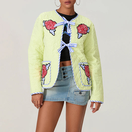 Light green quilted jacket with floral embellishments worn by a person on a plain background