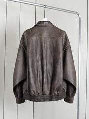Brown leather jacket on a hanger against a white wall