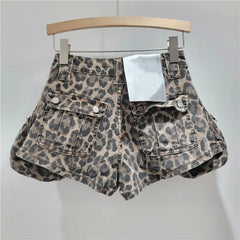 Leopard print denim shorts on a hanger against a plain background