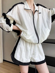 Person wearing a white and black tracksuit with a plain background