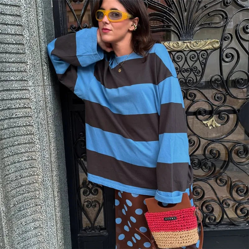 Person wearing a blue and brown striped sweater with a decorative background