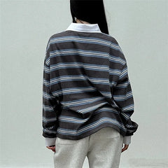 Person wearing a black and gray striped shirt with a plain background