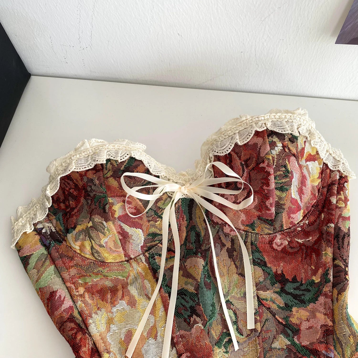 Floral patterned garment with lace details and a bow 