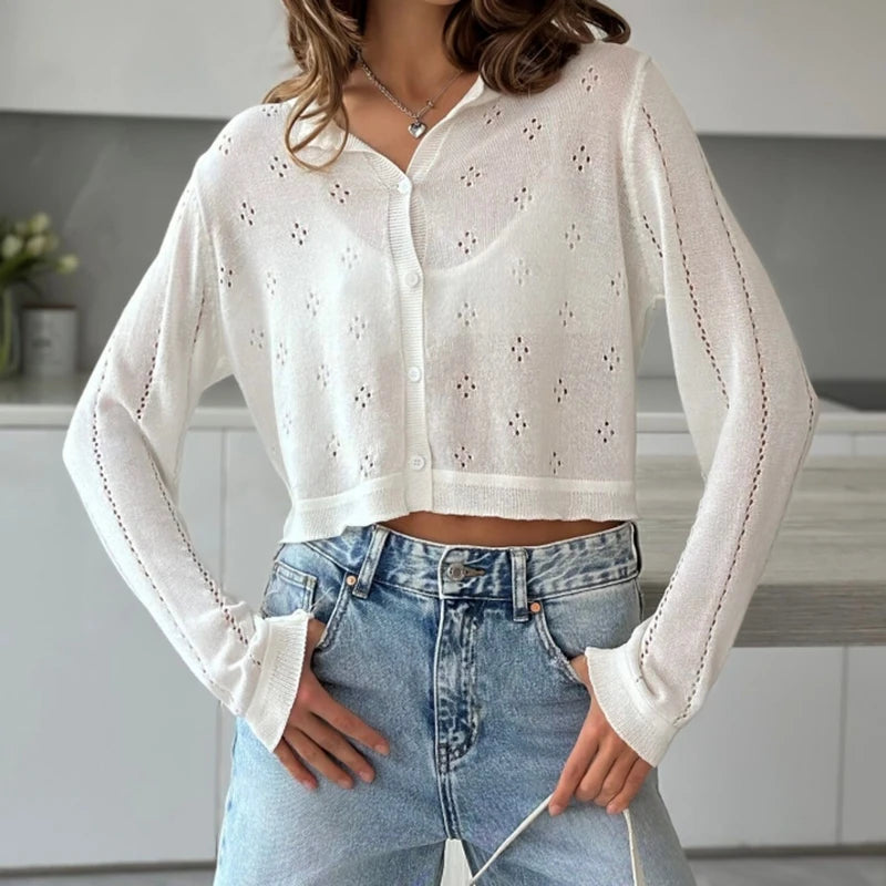 Person wearing a white embroidered blouse and blue jeans in a neutral setting