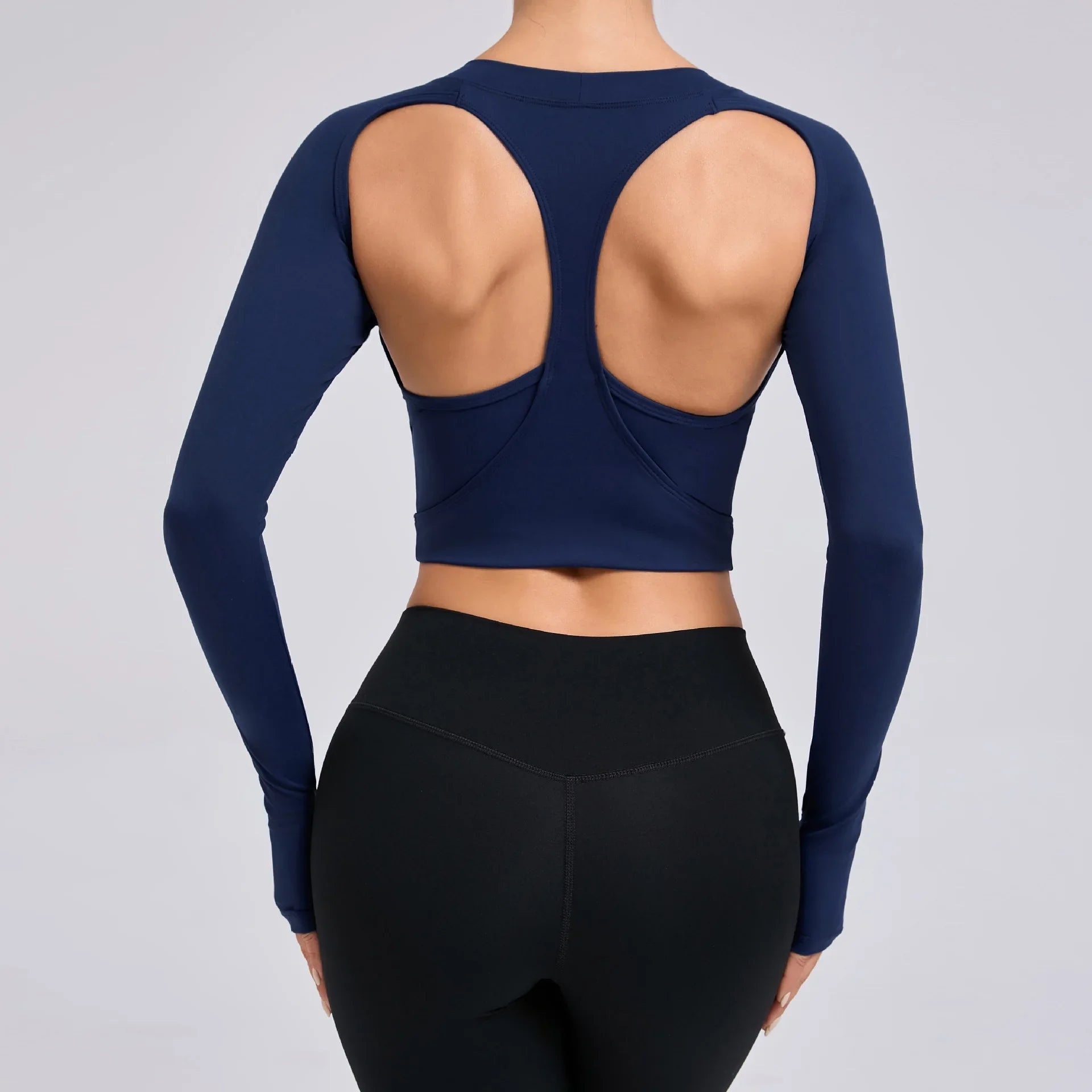Navy blue long-sleeve crop top with open back and black leggings on a gray background