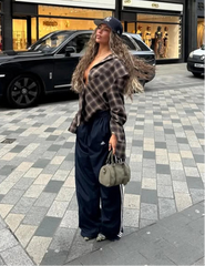 Person wearing a plaid shirt and black pants on a city street