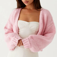 Woman wearing a pink knitted cardigan over a white top on a light background