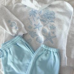 Light gray hoodie with blue ocean-themed designs and matching light blue pants on a neutral background