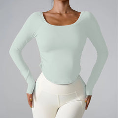 Person wearing a light green long-sleeve top and white pants on a gray background