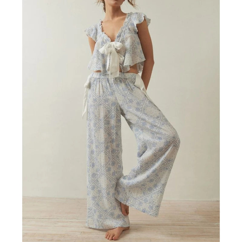 Woman wearing a light blue patterned outfit with ruffled top and wide-leg pants on a plain background