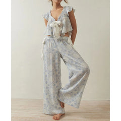 Woman wearing a light blue patterned outfit with ruffled top and wide-leg pants on a plain background