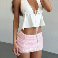 Person wearing a white top and pink sequin skirt against a plain background