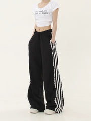 Person wearing a white crop top and black pants with white stripes 