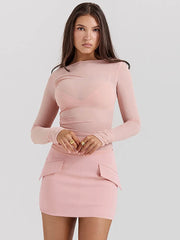 Woman wearing a pink dress with long sleeves on a light gray background