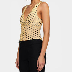 Woman wearing a beige tank top with black polka dots and black pants