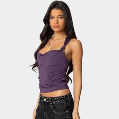 Woman wearing a purple halter top and black studded pants on a white background