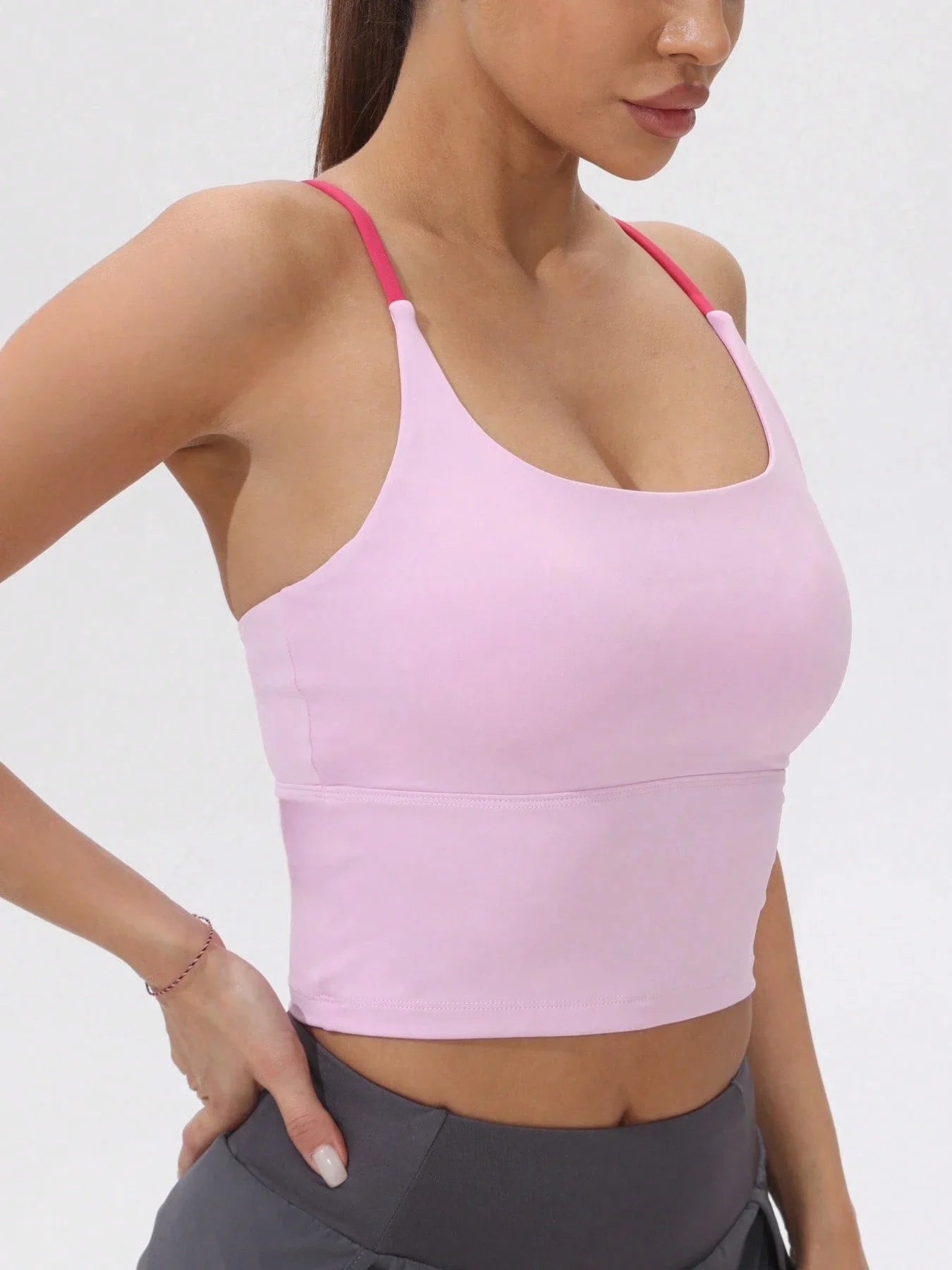 Woman wearing a pink sports bra and gray leggings - side view