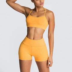 Woman wearing a yellow sports bra and shorts set on a light gray background