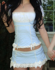 Person wearing a light blue checkered outfit with white lace details.