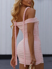 Pink off-shoulder dress with braided details on a blurred background