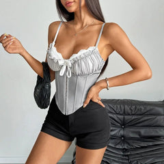 Woman wearing a gray corset top and black shorts against a neutral background