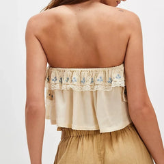 Beige strapless top with floral embroidery on a plain background