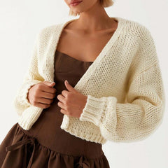 Woman wearing a beige knitted cardigan over a brown dress on a white background