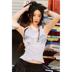 Person wearing a white sleeveless top with a graphic design, standing in a room with books and shelves.