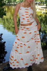 Woman wearing a white dress with goldfish pattern by a body of water.
