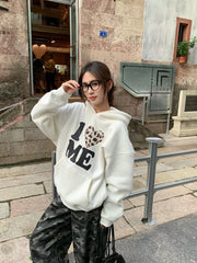 Person wearing a white hoodie with 'I ❤️ ME' text, standing on a street.