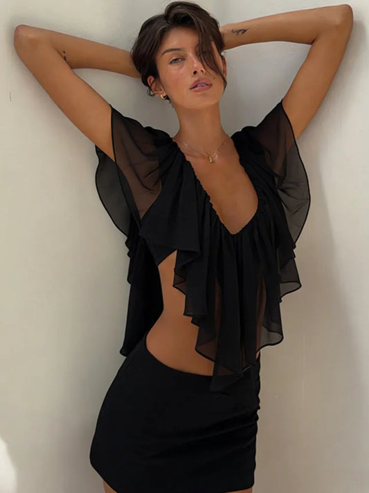 Woman wearing a black sheer top and skirt against a plain background
