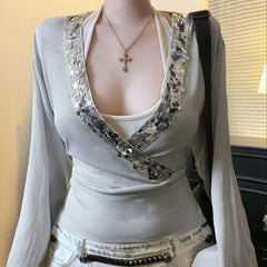 Mannequin wearing a gray long-sleeve top with decorative front panel and white pants.