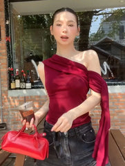 Woman in a red top holding a red handbag outdoors.