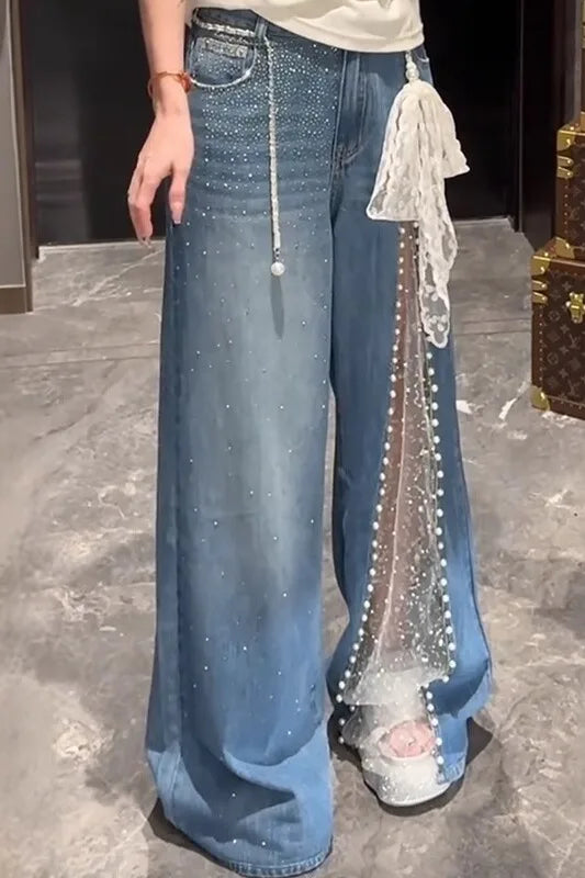Person wearing blue jeans with decorative elements on a marble floor.