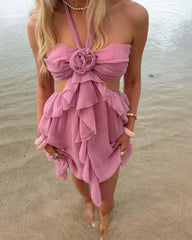 Woman wearing a pink dress with floral details on a beach.