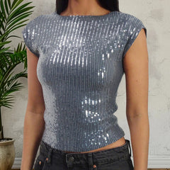 Person wearing a silver sequin top against a neutral background