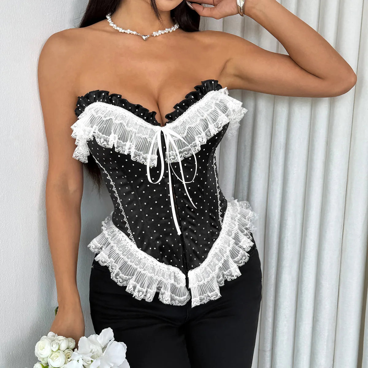 Black lace corset worn by a model against a white curtain background
