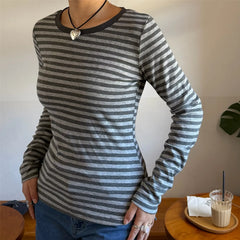 Person wearing a gray and black striped long-sleeve shirt with a plain background