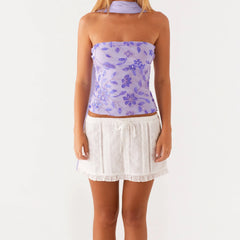 Woman wearing a floral purple top and white skirt