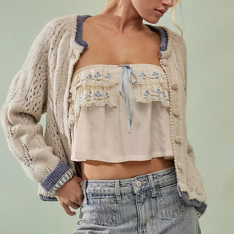 Person wearing a beige embroidered top and cardigan with blue accents on a light green background