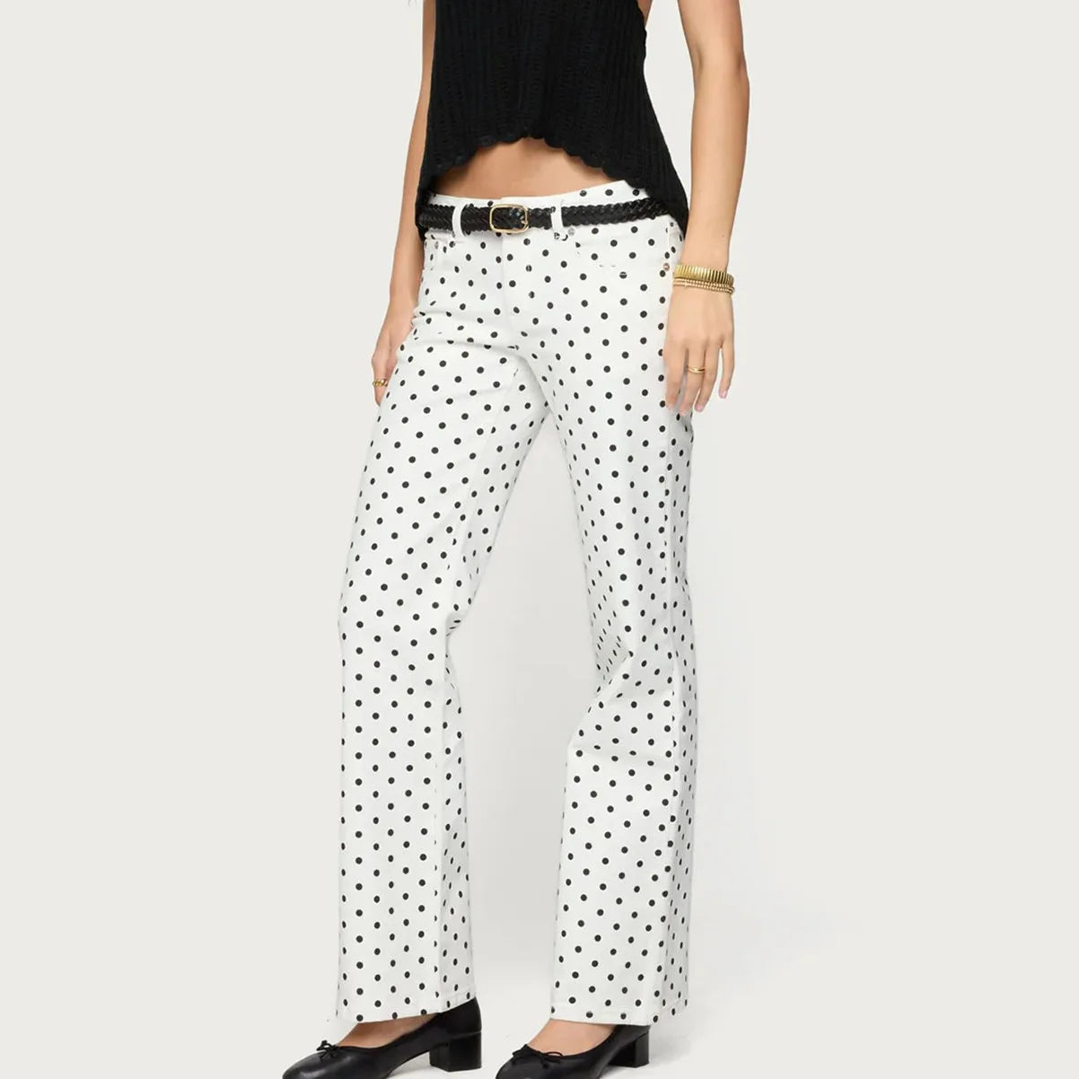 White pants with black polka dots worn by a person on a white background