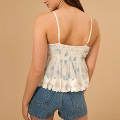 Woman wearing a floral top and denim shorts against a beige background