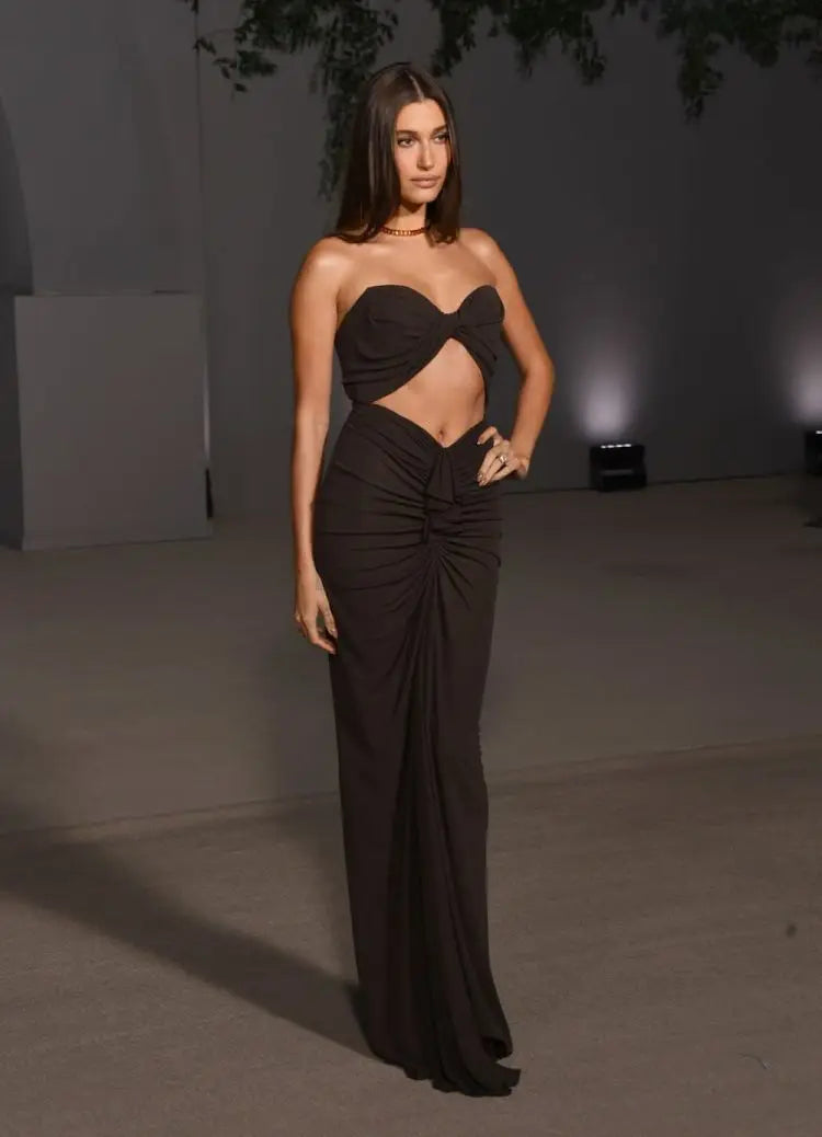 A woman wearing a black strapless dress with a flowing silhouette and unique cutouts, perfect for a special occasion.