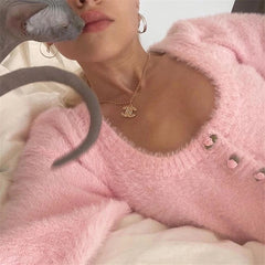 Person wearing a pink sweater with a heart design, holding a gray snake.