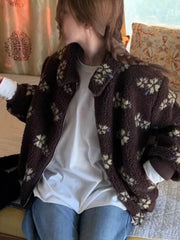 Person wearing a brown patterned cardigan over a white shirt and blue jeans, sitting on a couch.