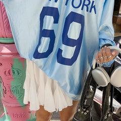 A woman wearing a blue jersey top with white skirt, showcasing its versatility and casual style.